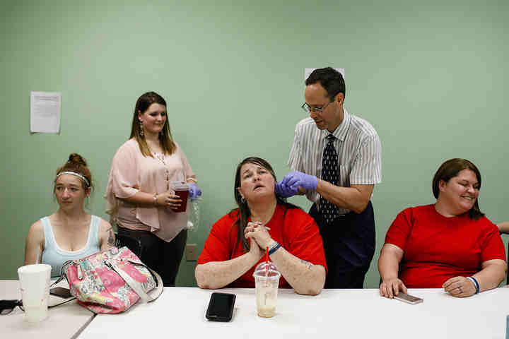 Carla Riffle (center) of Circleville, relaxes as Dr. Kenneth J. Laux, (second from right) removes needles from her ear at the end of an acupuncture treatment at Pickaway Area Recovery Services in Circleville. With the help of grant money, Dr. Laux began using acupuncture as a way to help treat people recovering from opioid disorder.   (Joshua A. Bickel / The Columbus Dispatch)